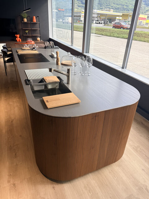 Plan de travail inox massif Franke à évier intégré sur îlot en noyer, showroom Noblessa à Conthey