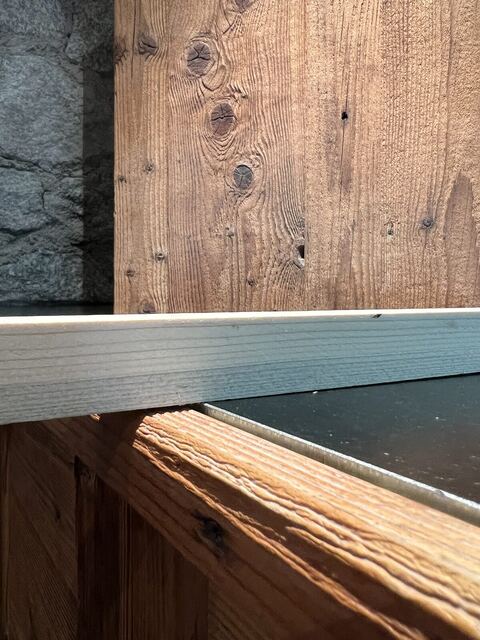 Détail d'un plan de travail inox noir contre du vieux bois