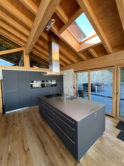 Plan de travail inox massif Franke à évier intégré sur îlot, avec plan de cuisson et mitigeur, dans un chalet à Nendaz