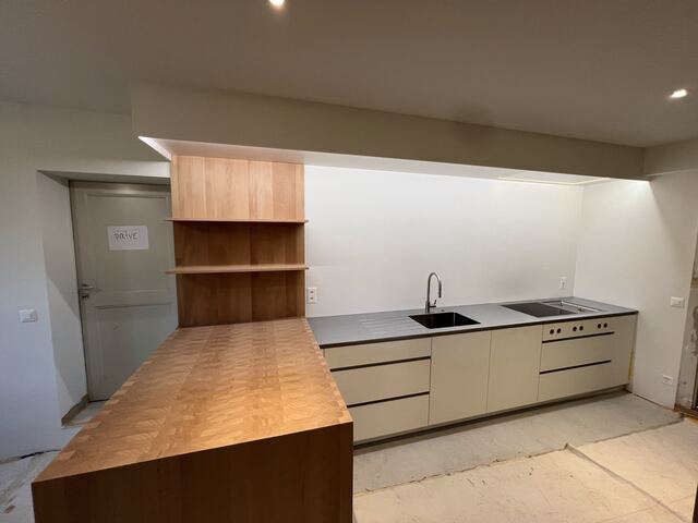 Plan de travail inox dans une cuisine bois et blanc