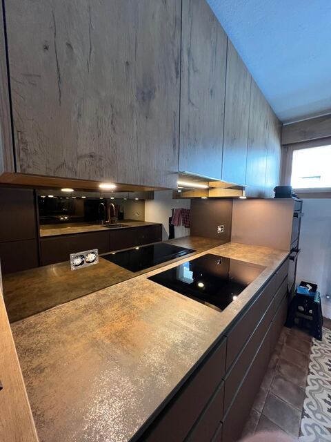 Plan de travail inox dans une cuisine sombre à plafond bois