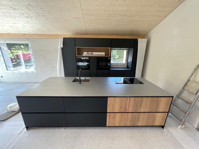 Plan de travail inox sur un grand îlot noir et bois